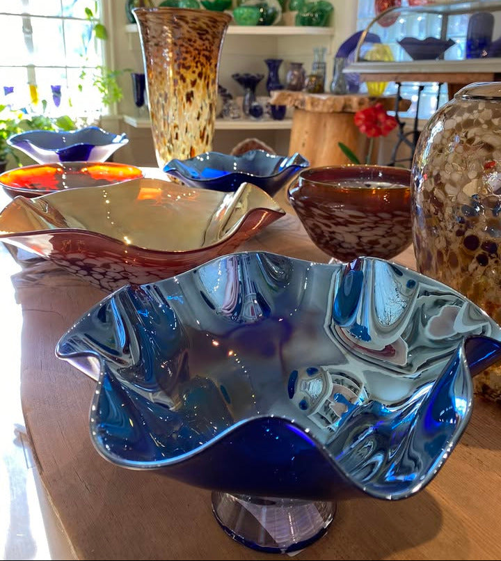 Collection of glassware including bowls and vases on a table with a blurred background.